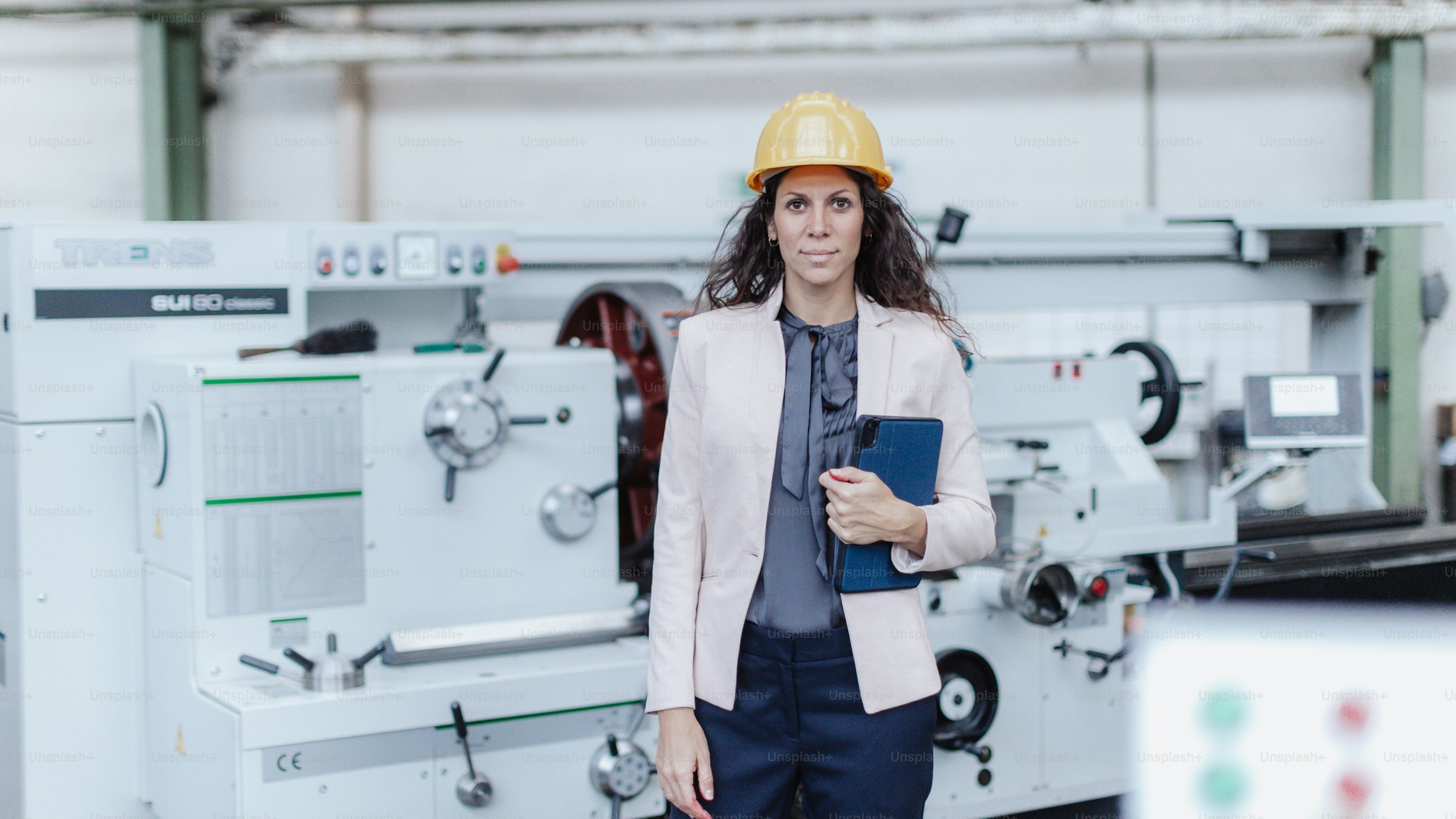 Modern manufacturing facility with an engineer using a tablet beside precision machinery